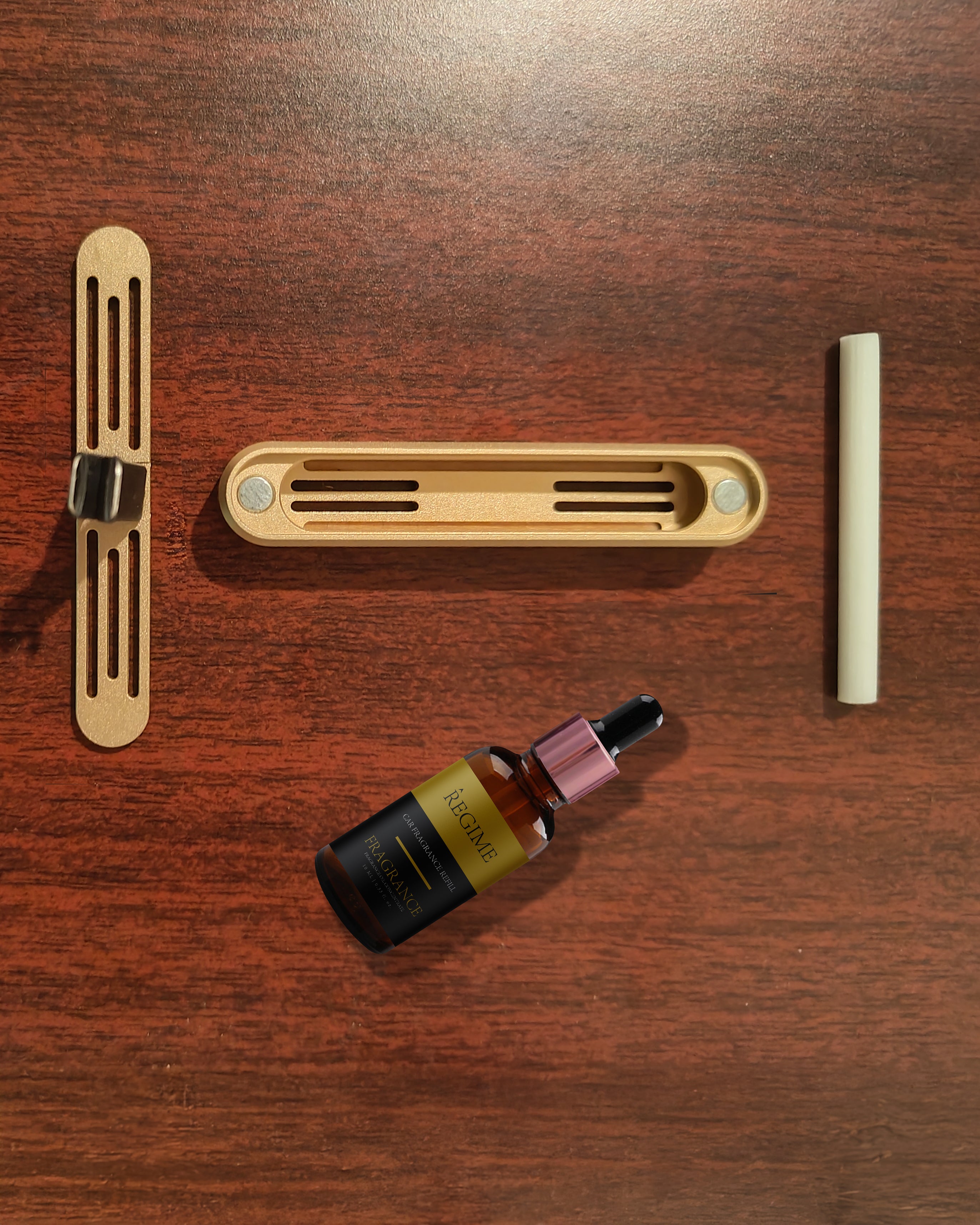 Component view of Regime Fragrances rose gold car clip with scent insert and oil.